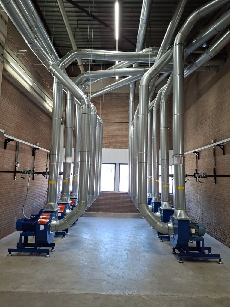 Industrial warehouse with large metal HVAC ductwork system and pumps installed in a brick corridor